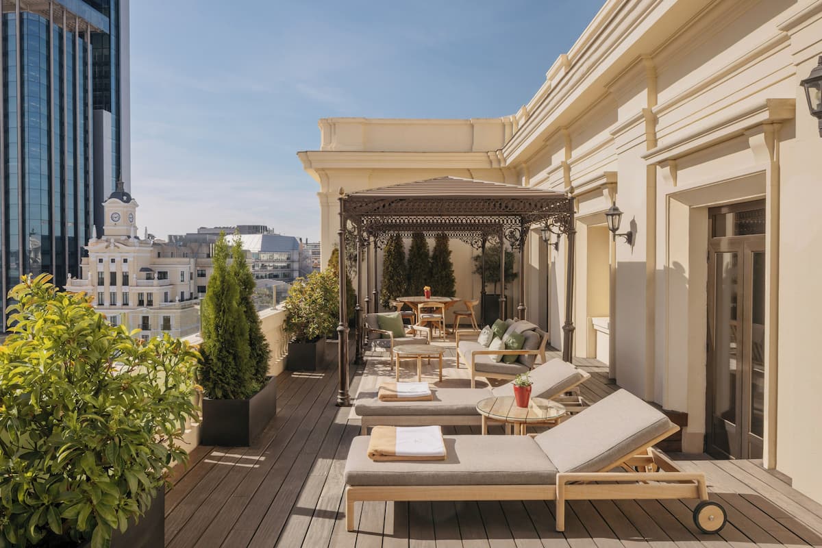 Une terrasse sur le toit, dotée de chaises longues, d’une pergola et de plantes en pot.