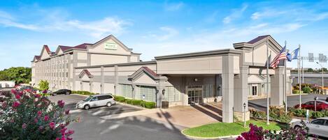 A hotel with a modern design, featuring a prominent entrance and a parking lot.