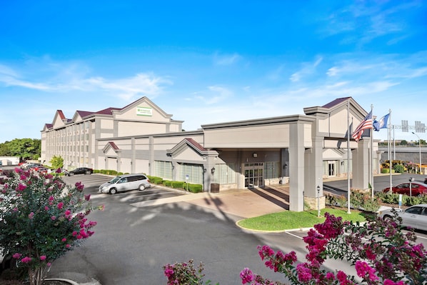 A hotel with a modern design, featuring a prominent entrance and a parking lot.