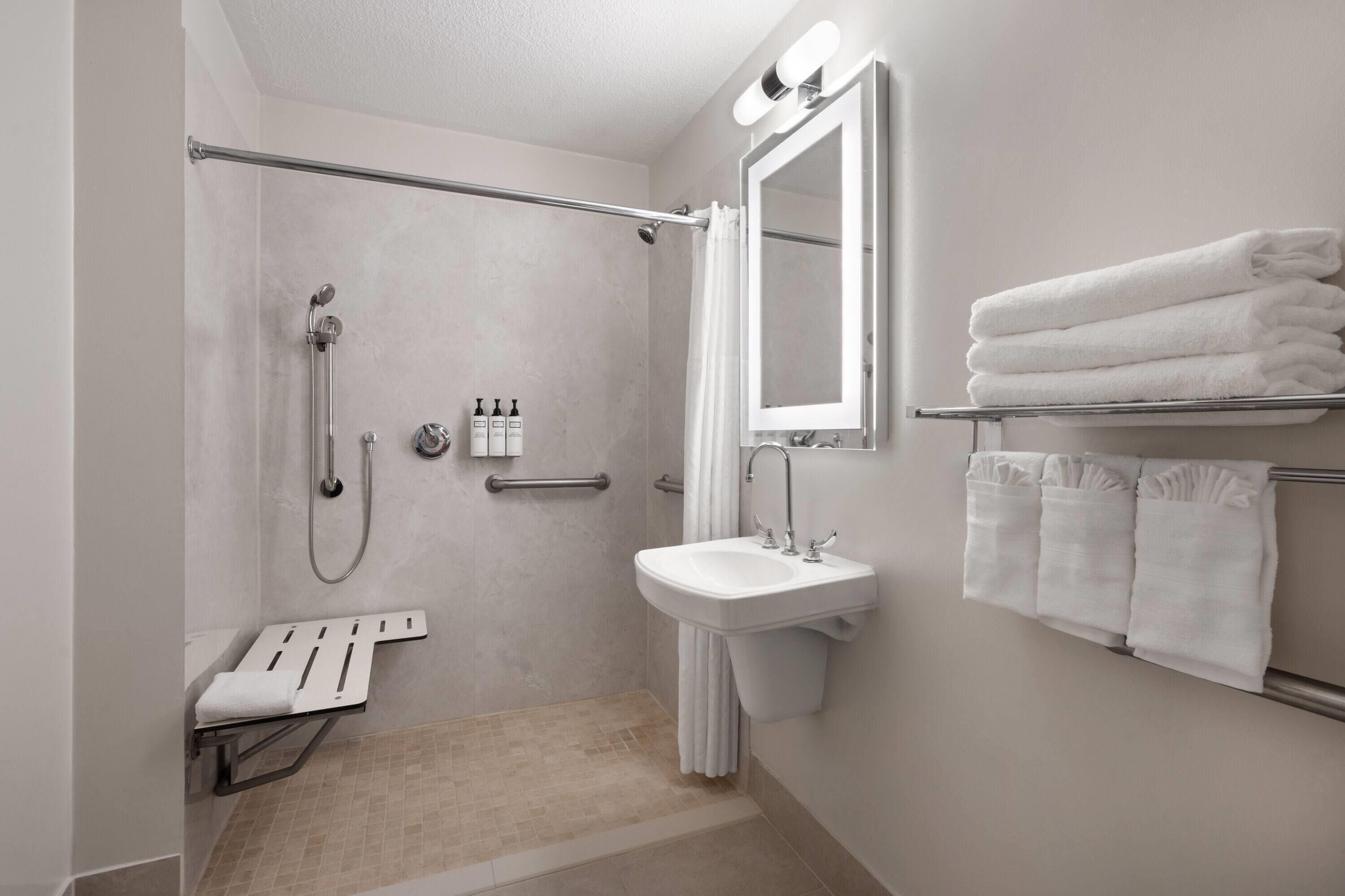 Un baño moderno con cabina de ducha, lavabo y espejo.