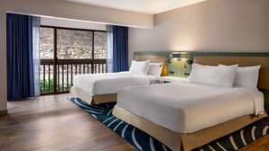 A hotel room with two beds, a balcony with a stone wall, and a view of greenery. - Hilton Garden Inn Monterey (Monterey)