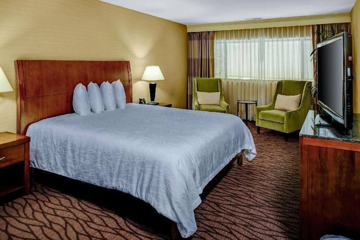 A hotel room with a large bed, two chairs, a TV, and a small table.