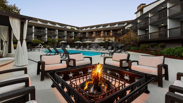 A poolside area with lounge chairs, a fire pit, and a pool. - Hilton Garden Inn Monterey (Monterey)