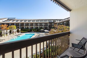 A hotel courtyard with a swimming pool, lounge chairs, and a building with multiple balconies. - Hilton Garden Inn Monterey (Monterey)