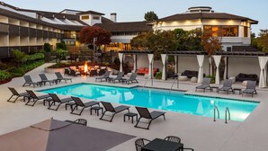 A pool area with lounge chairs, a fire feature, and a covered seating area. - Hilton Garden Inn Monterey (Monterey)