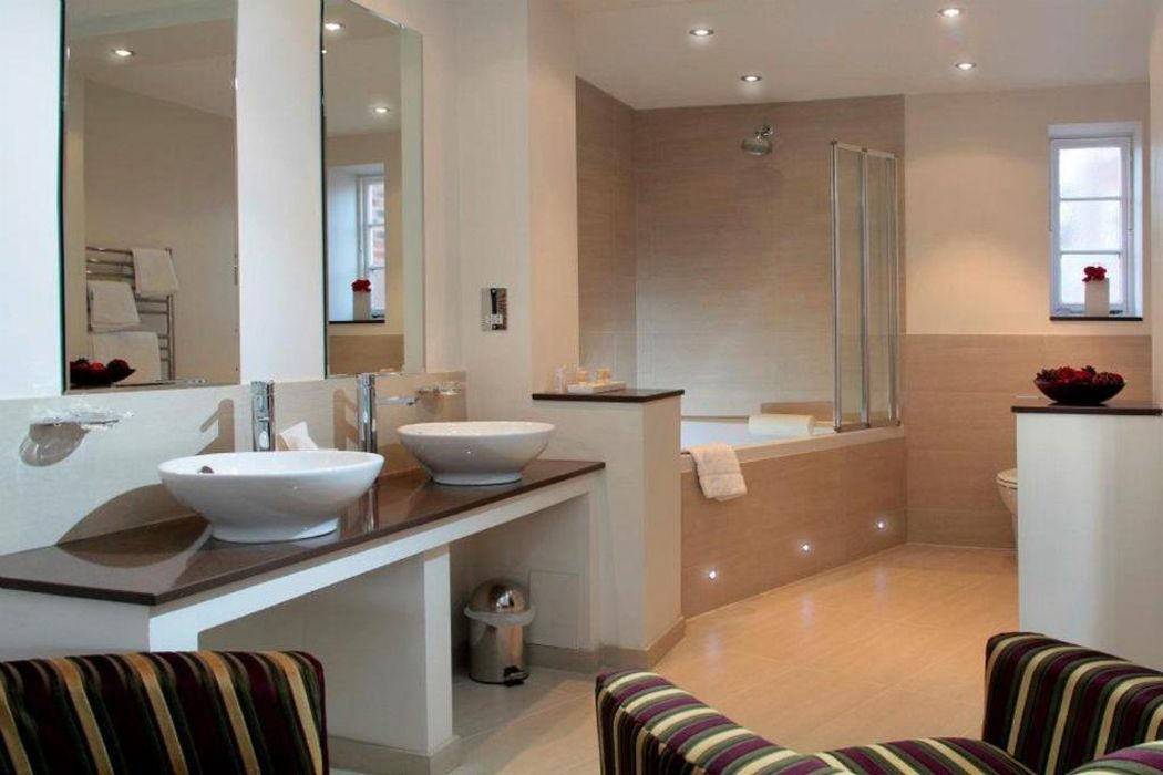 A modern bathroom with two sinks, a large mirror, a bathtub, and a shower.
