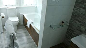 A modern bathroom with a toilet, bathtub, and shower area.