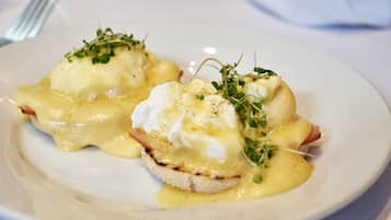 A plate of eggs benedict with hollandaise sauce and garnished with herbs.