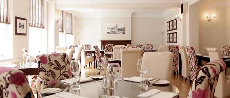 Un espace repas avec des tables rondes disposées pour accueillir quatre personnes, entourées de chaises ornées de motifs floraux.