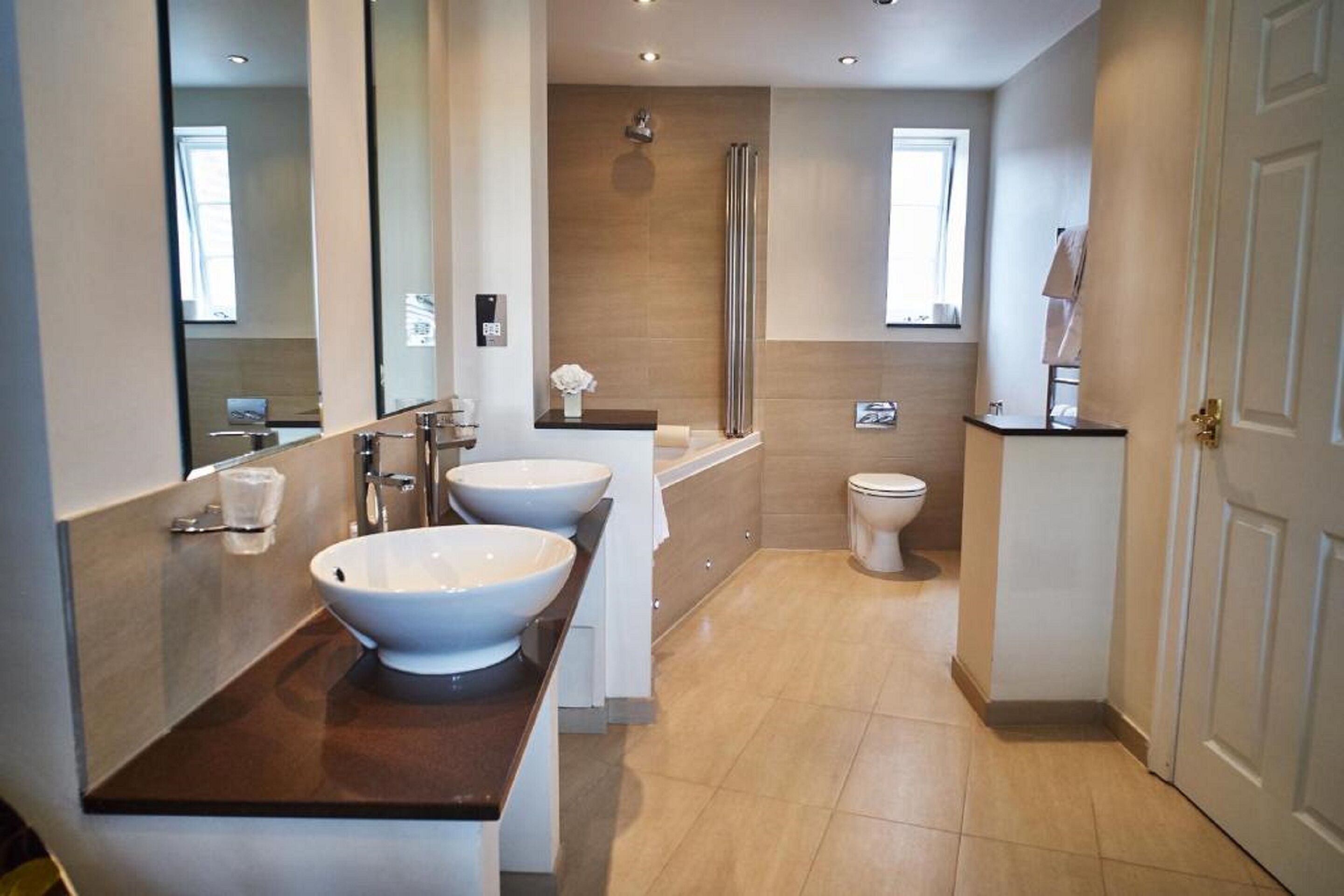 A modern bathroom with two large sinks, a shower, and a toilet.