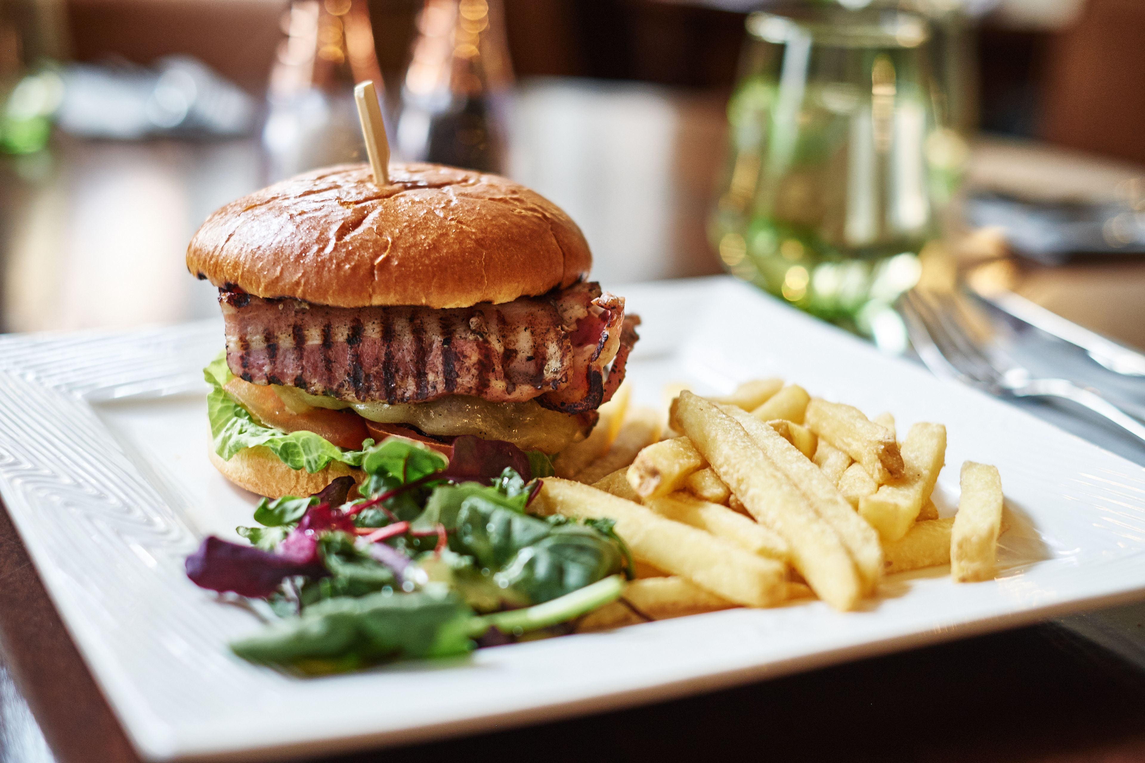 A plate with a burger, fries, and a side salad.