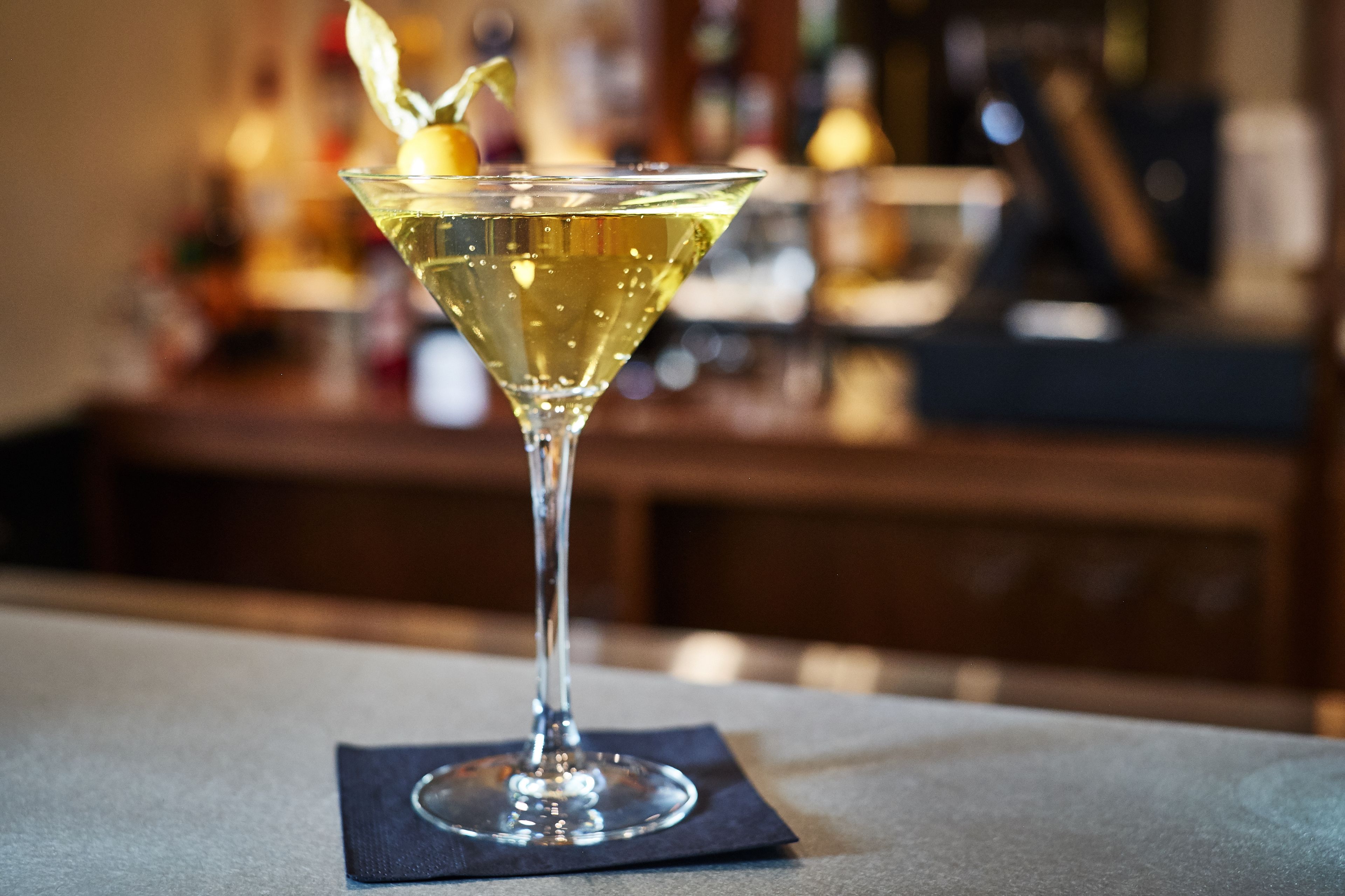 A martini glass with a lemon twist on a bar counter.