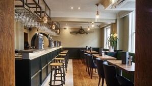 A bar area with stools, a counter, and hanging glasses. There are tables and chairs for dining. - The Chequers Hotel (Newbury)