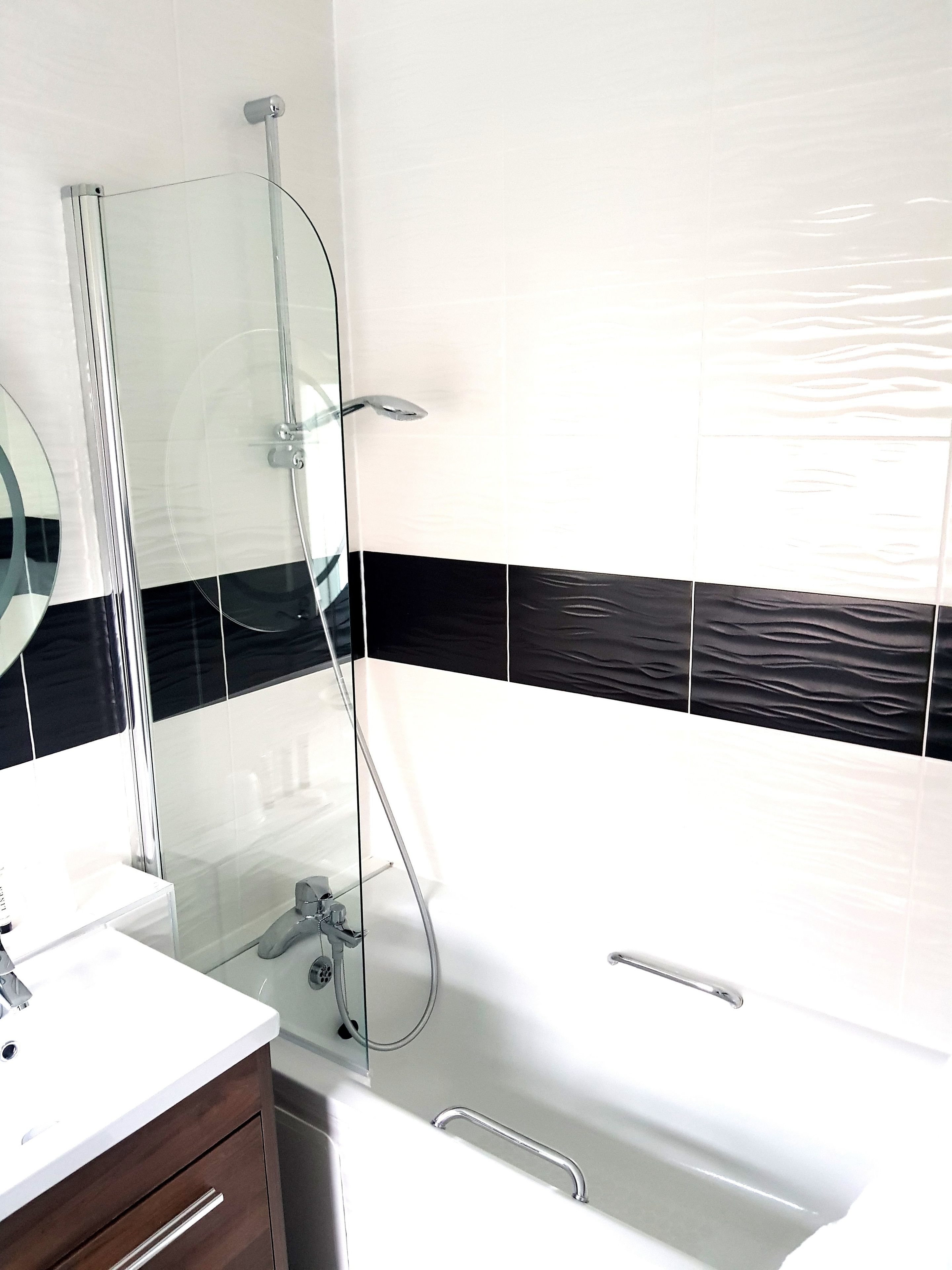 Un baño moderno con cabina de ducha de vidrio, una bañera blanca y un tocador con espejo.