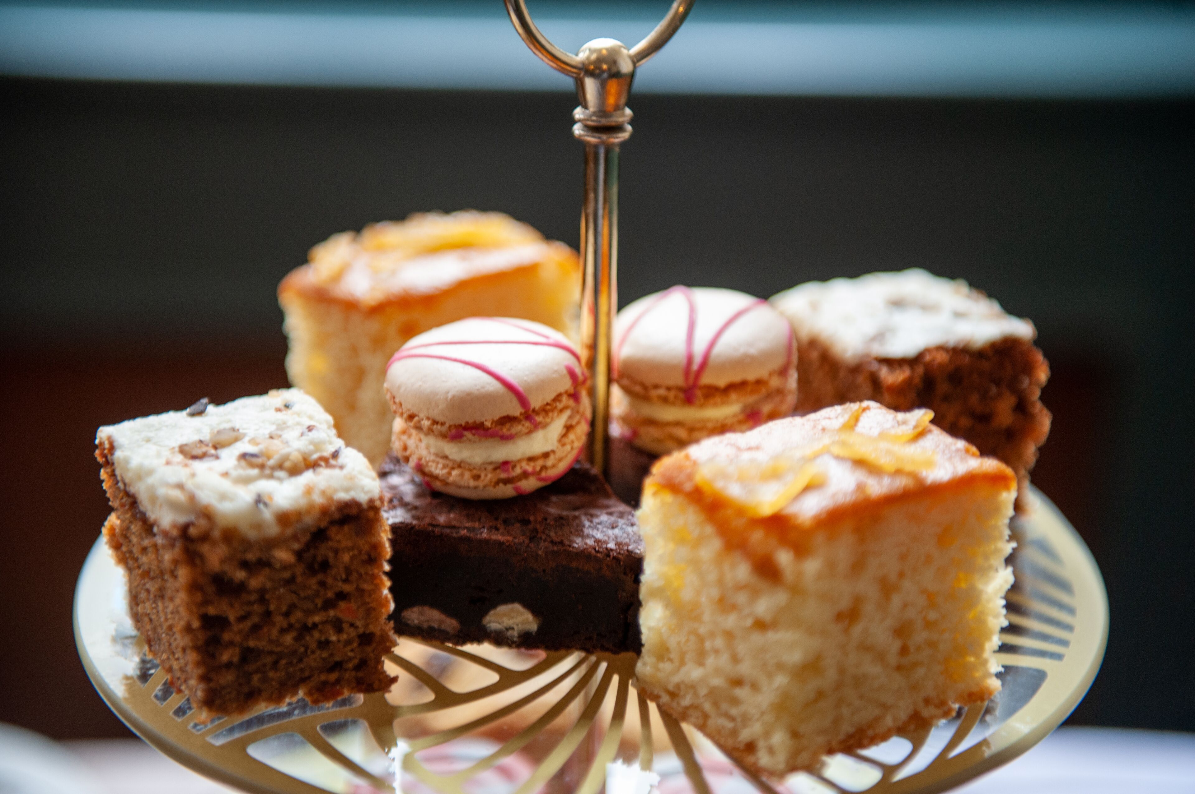 A variety of desserts on a glass plate, including macarons and cakes.