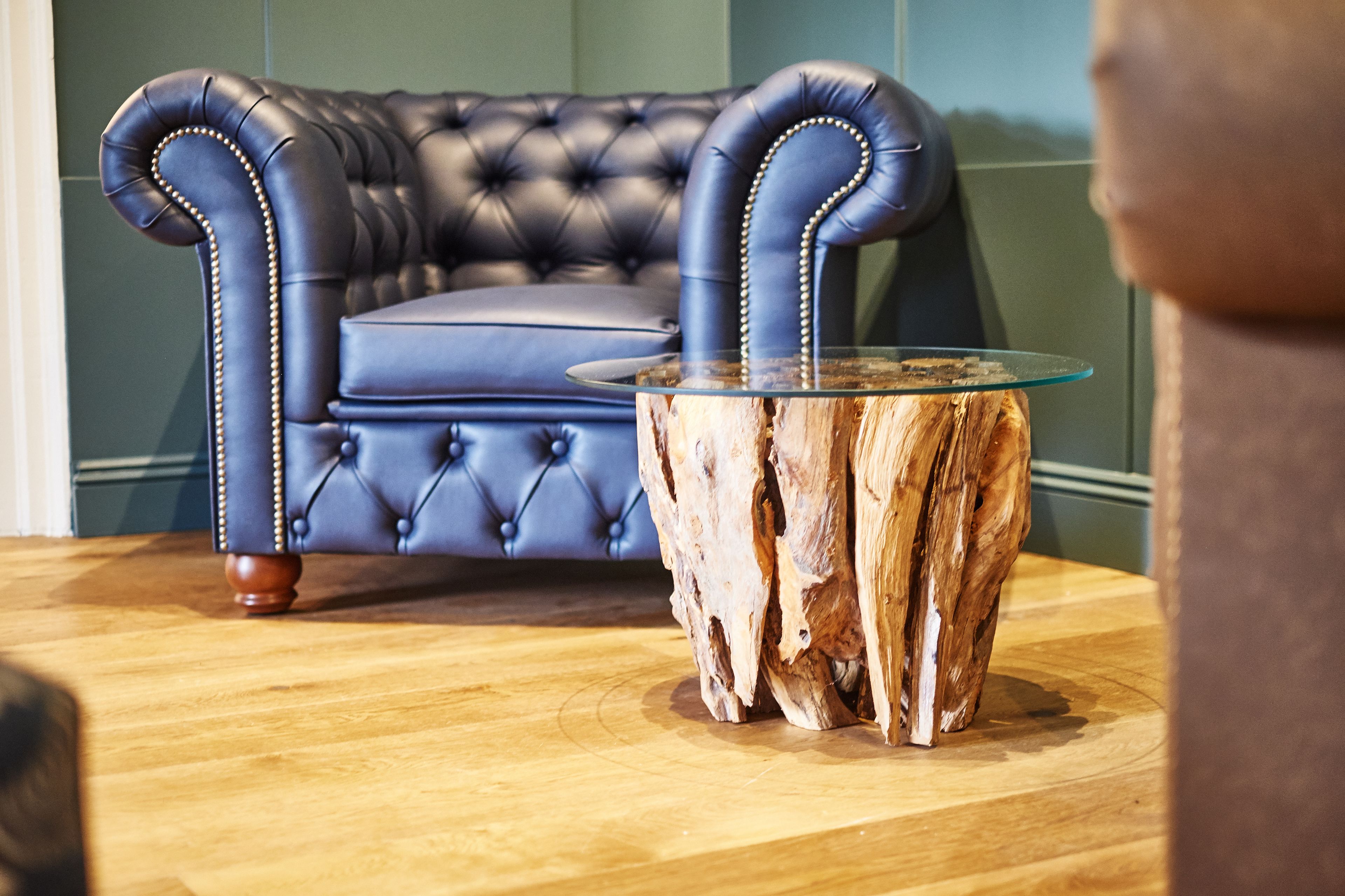 A tufted leather sofa with a glass coffee table in front.
