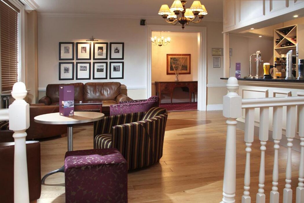 A hotel lobby with leather sofas, striped armchairs, a round table, and a chandelier.