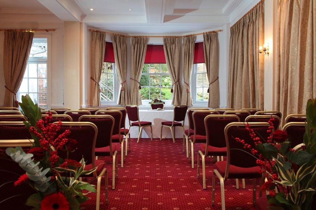 A conference room with red chairs, a table, and curtains.