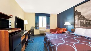 A hotel room with a bed, desk, chair, and a television.