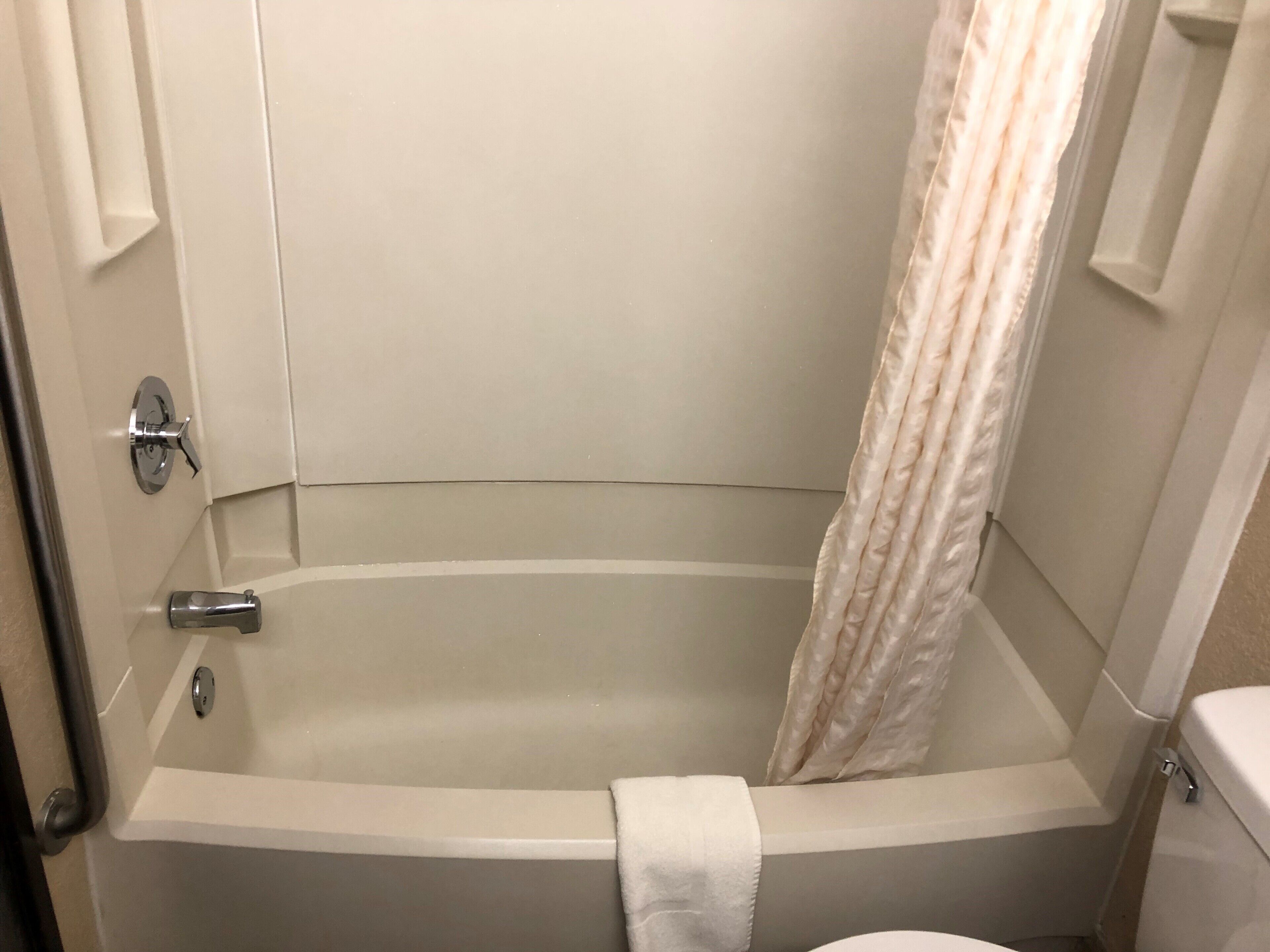 Un baño con bañera, inodoro y cortina de ducha.