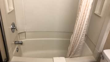 Un baño con bañera, inodoro y cortina de ducha.