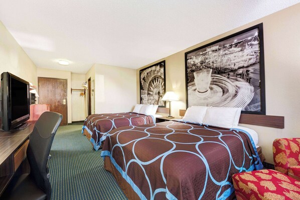 Habitación de hotel con una cama grande, un escritorio con televisor, una silla y un cuadro grande en la pared.