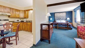 A compact hotel room with a kitchenette, a dining area, a bed, and a bathroom.
