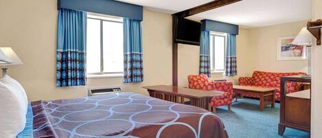 Ein Hotelzimmer mit einem großen Bett, einer Couch, einem Schreibtisch und einem Fernseher.