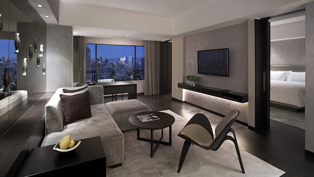 A modern hotel room with a city view, a large bed, a seating area with a coffee table, and a TV mounted on the wall. - New World Makati Hotel (Makati)