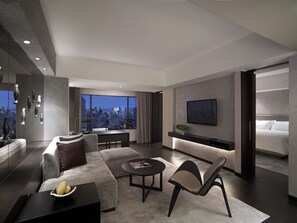 A modern hotel room with a city view, a large bed, a seating area with a coffee table, and a TV mounted on the wall. - New World Makati Hotel (Makati)