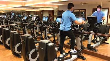 A gym with multiple treadmills, a mirrored wall, and a wooden floor.