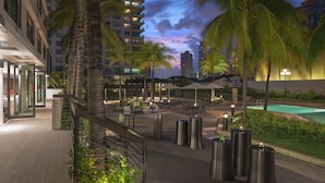 A modern outdoor area with seating, palm trees, and a pool.