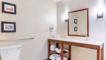 A bathroom with a toilet, a sink with a mirror, and shelves with towels.