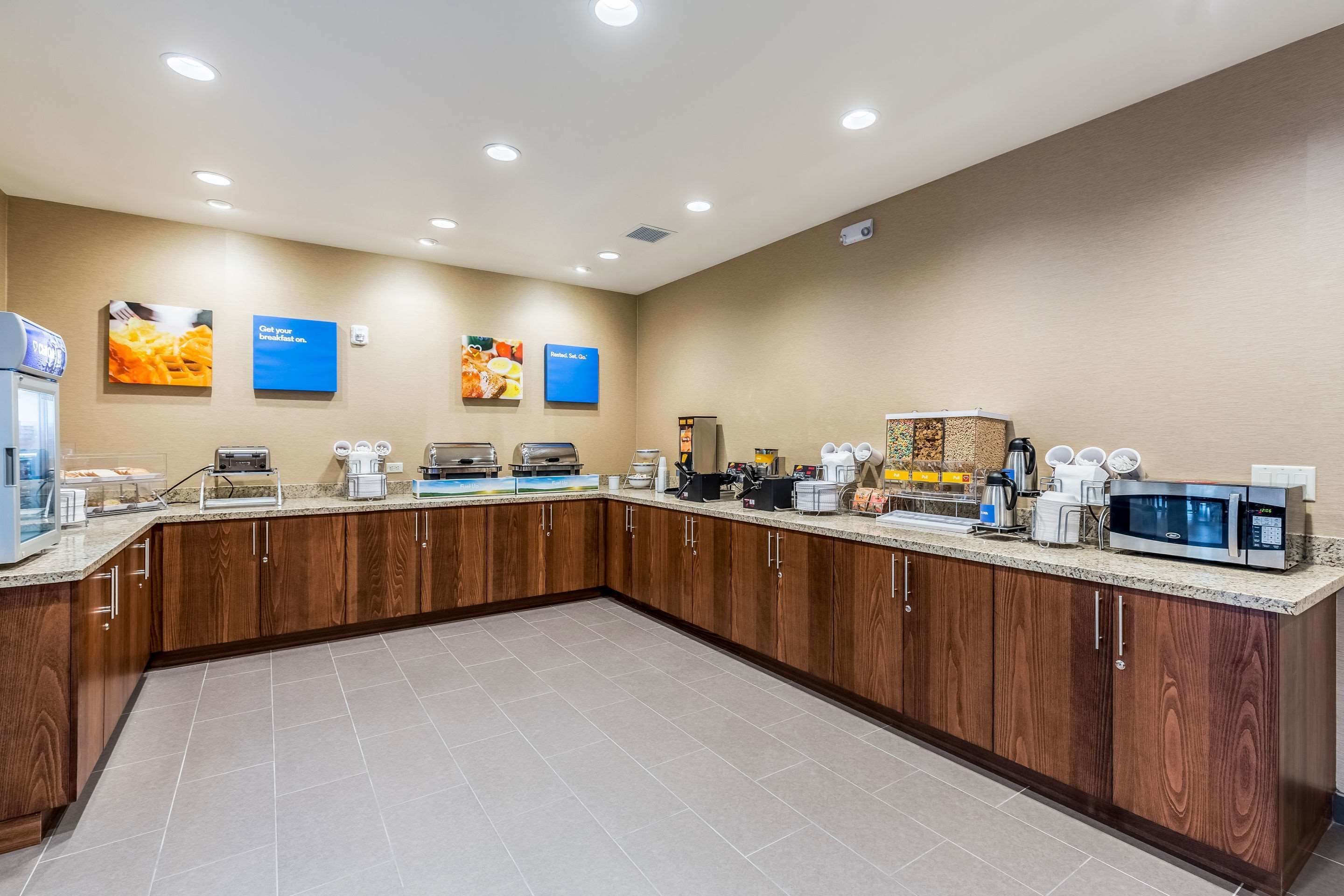 A modern kitchen with wooden cabinets, a granite countertop, and various appliances like a coffee maker, microwave, and toaster.