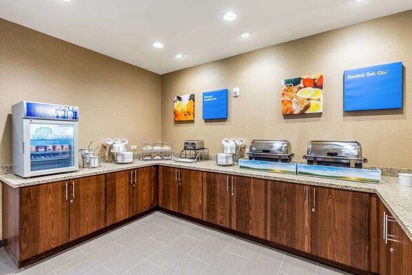 A hotel breakfast area with a self-service station, coffee makers, and a refrigerator. - Comfort Suites St George - University Area (St. George)