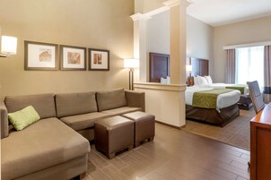 Habitación de hotel con sofá, dos camas, un espejo y cuadros en la pared.