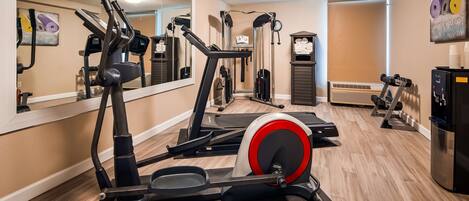 A gym with various exercise equipment including treadmills, a stationary bike, and free weights.