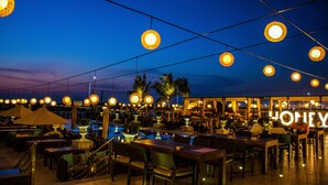 An outdoor dining area with tables and chairs, a pool, and hanging lights. - The Kingsbury Colombo (Colombo)