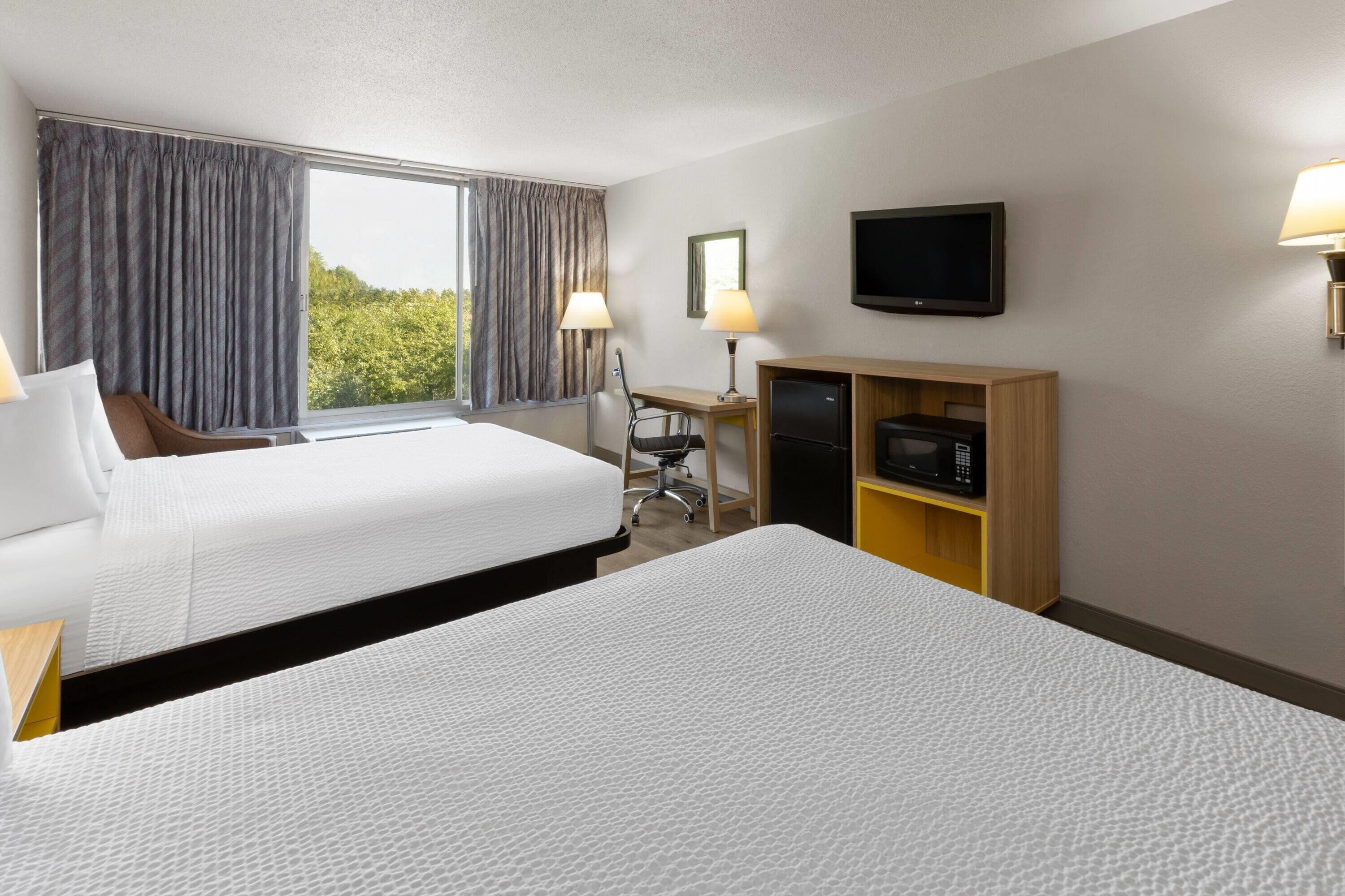 Habitación de hotel con dos camas, un escritorio, una silla, un televisor y un minibar.
