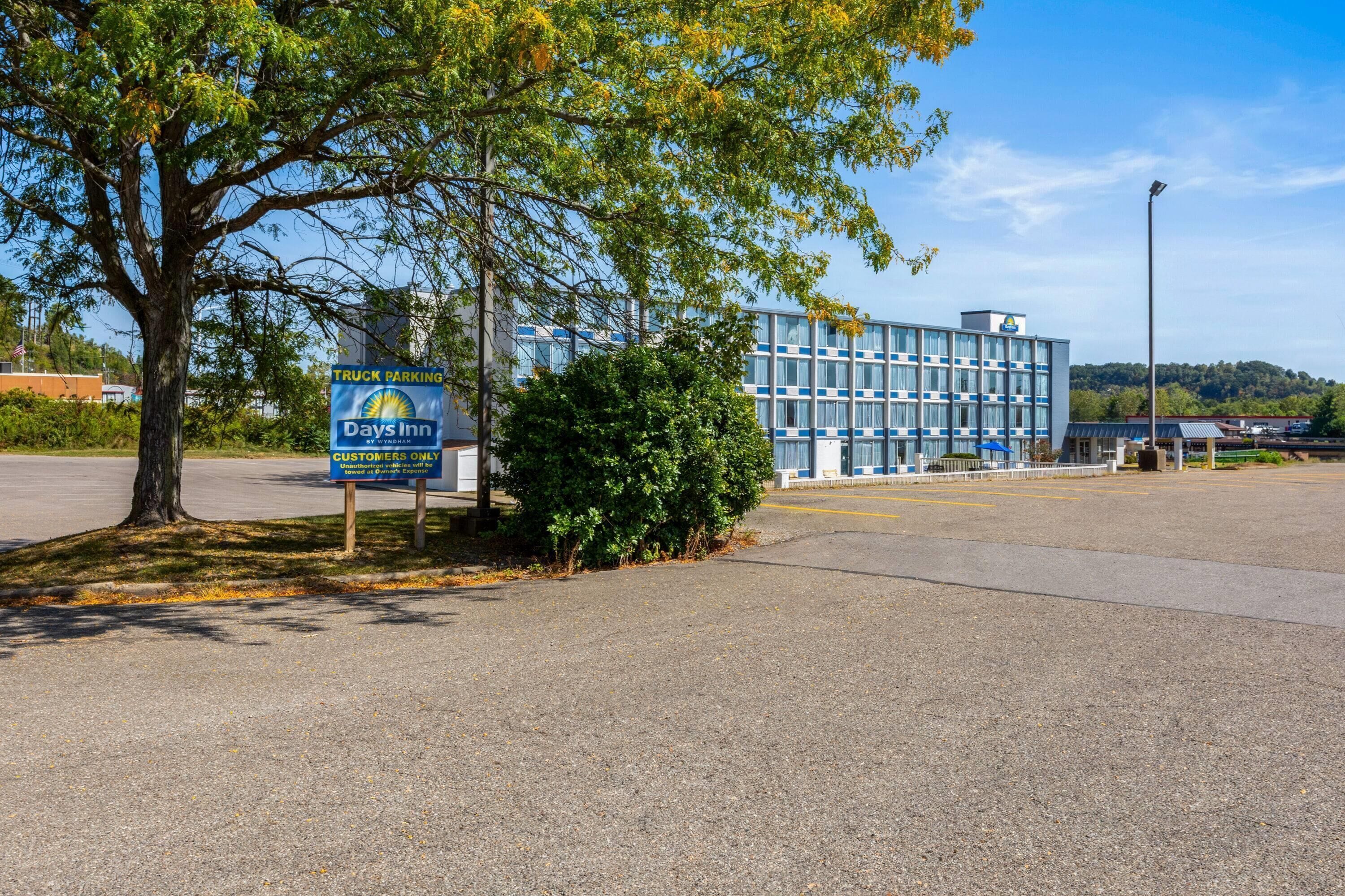 En skylt för Days Inn som visar att parkering endast är tillåten för lastbilar som tillhör hotellets gäster, och framför byggnaden finns en parkeringsplats intill en modern byggnad.
