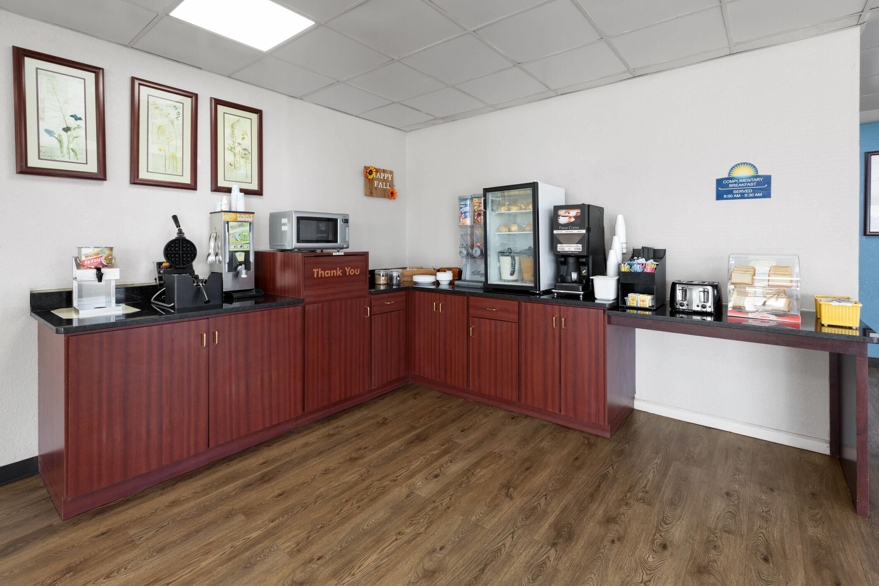A kitchen area with wooden cabinets, a microwave, a coffee machine, and a refrigerator.