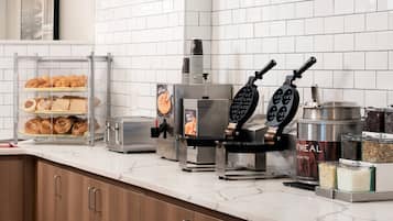 Un bar pour le petit-déjeuner équipé d’un appareil à gaufres, d’un grille-pain et d’une machine à café.