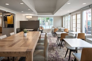 A modern conference room with a long wooden table, several chairs, and a large window providing a view of the outdoors. - Residence Inn Las Vegas Convention Center by Marriott (Las Vegas)