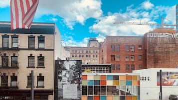 A multi-story building with a mix of brick and modern glass facades, a large American flag, and a crane in the background.