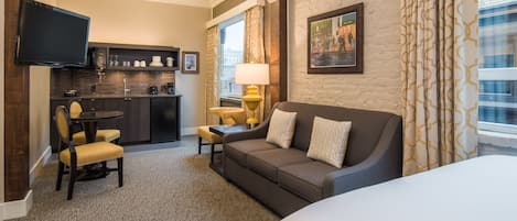 A hotel room with a sofa, armchair, and a small dining table.