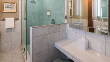 A modern bathroom with a glass shower enclosure, a white sink, and a large mirror.