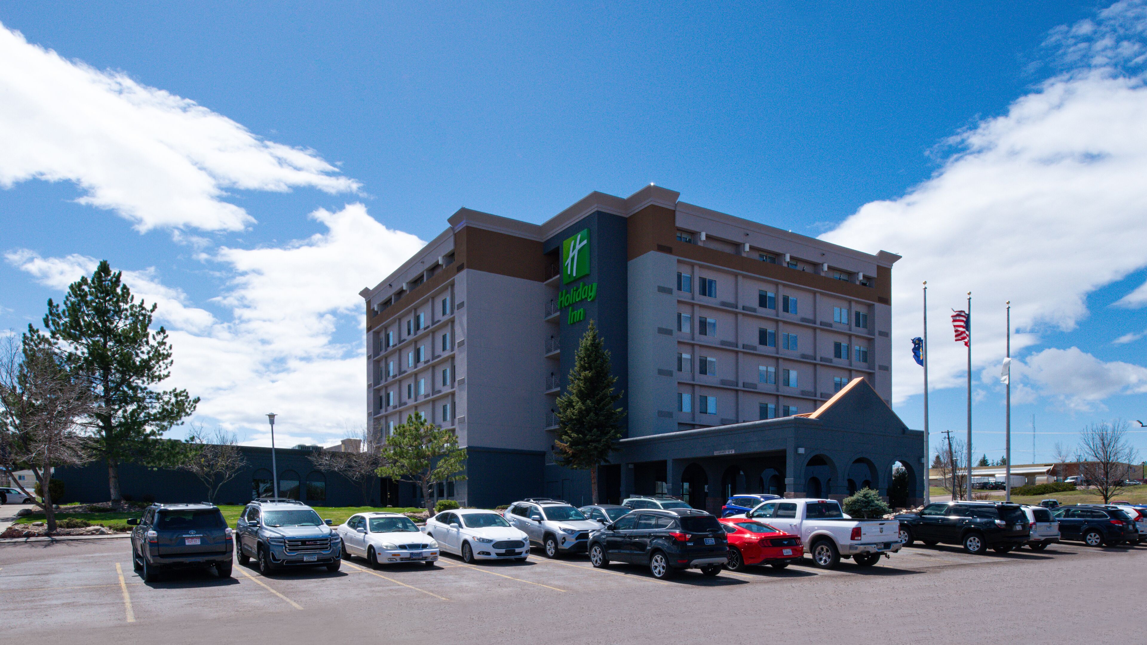 Un hotel Holiday Inn con un estacionamiento lleno de coches.