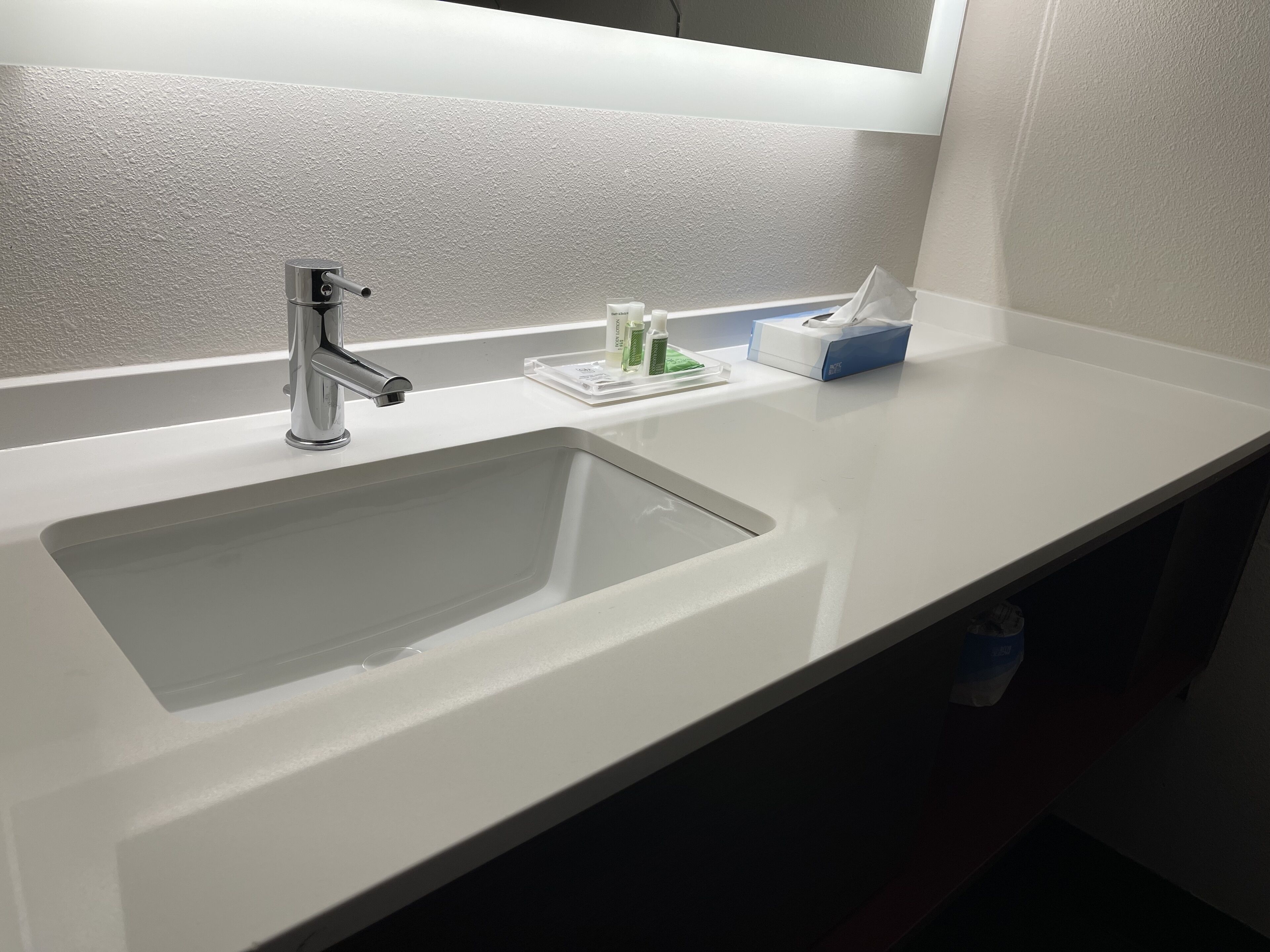 A modern bathroom with a white sink, chrome faucet, and a mirror above.