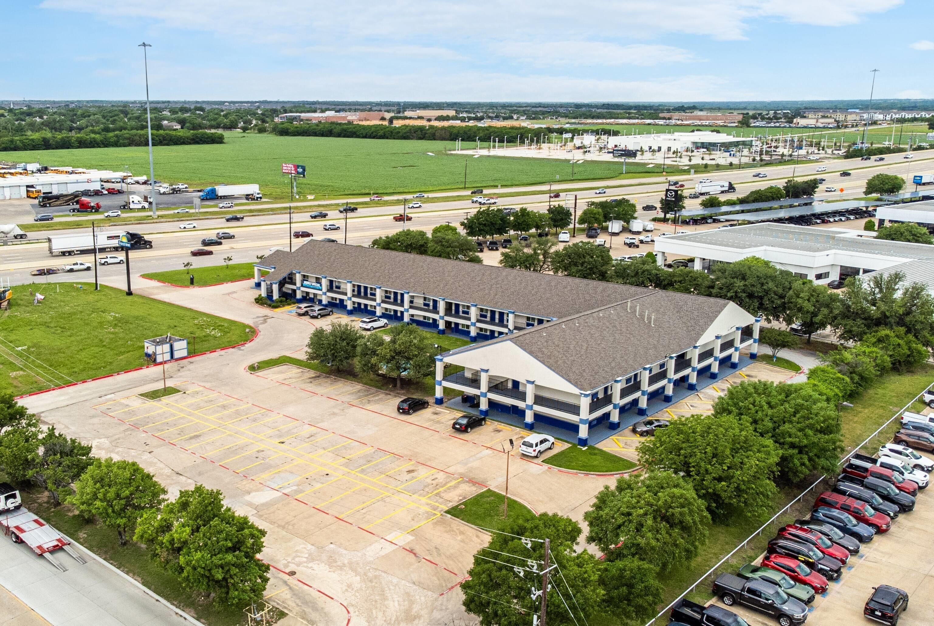 Luchtbeeld van een parkeerplaats met een groot gebouw ernaast.
