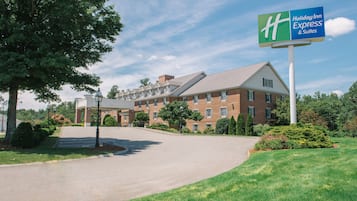 A Holiday Inn Express & Suites hotel with a brick facade, a covered parking area, and a well-maintained lawn.